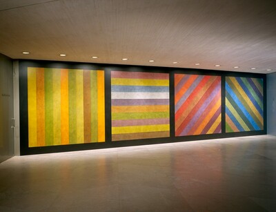 Wall Drawing No. 681 C / A wall divided vertically into four equal squares separated and bordered by black bands. Within each square, bands in one of four directions, each with color ink washes superimposed.